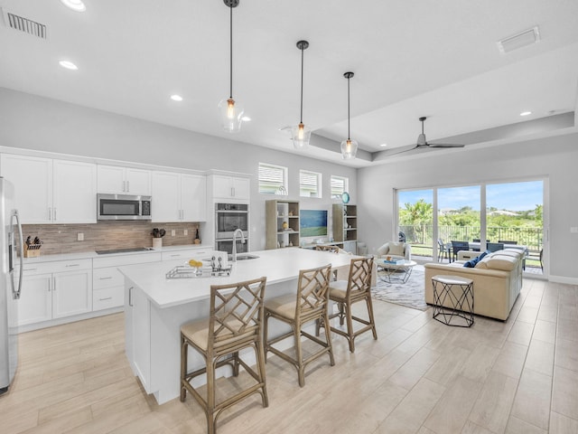12495 SW Sunrise Lake Ter, Port Saint Lucie, FL 34987 - kitchen with appliances with stainless steel finishes, open floor plan, light wood-type flooring, backsplash, and light countertops