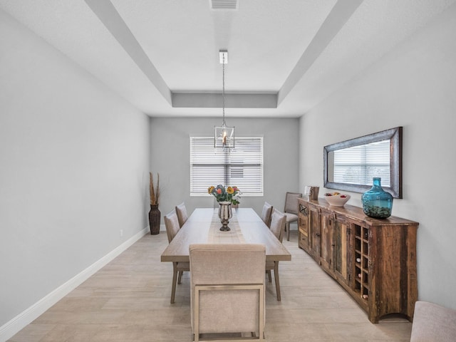 12495 SW Sunrise Lake Ter, Port Saint Lucie, FL 34987 - dining room featuring a raised ceiling, light wood finished floors, baseboards, and a chandelier
