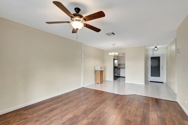 2811 Ashley Dr E Unit E, West Palm Beach, FL 33415 - unfurnished living room featuring baseboards, ceiling fan with notable chandelier, light wood-type flooring, and visible vents