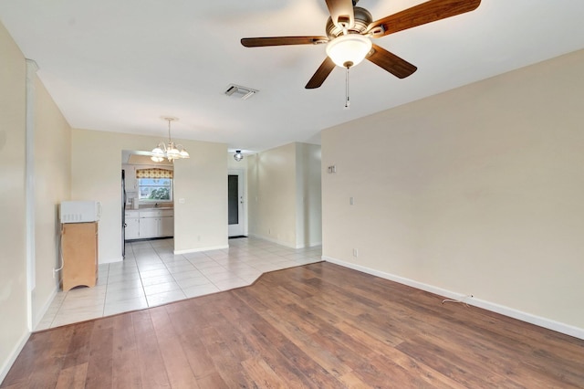 2811 Ashley Dr E Unit E, West Palm Beach, FL 33415 - unfurnished room featuring visible vents, light wood finished floors, ceiling fan with notable chandelier, and baseboards