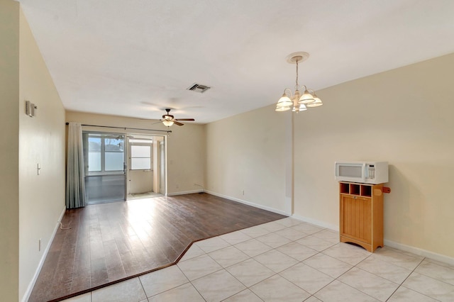 2811 Ashley Dr E Unit E, West Palm Beach, FL 33415 - empty room with baseboards, visible vents, light wood-style flooring, and ceiling fan with notable chandelier