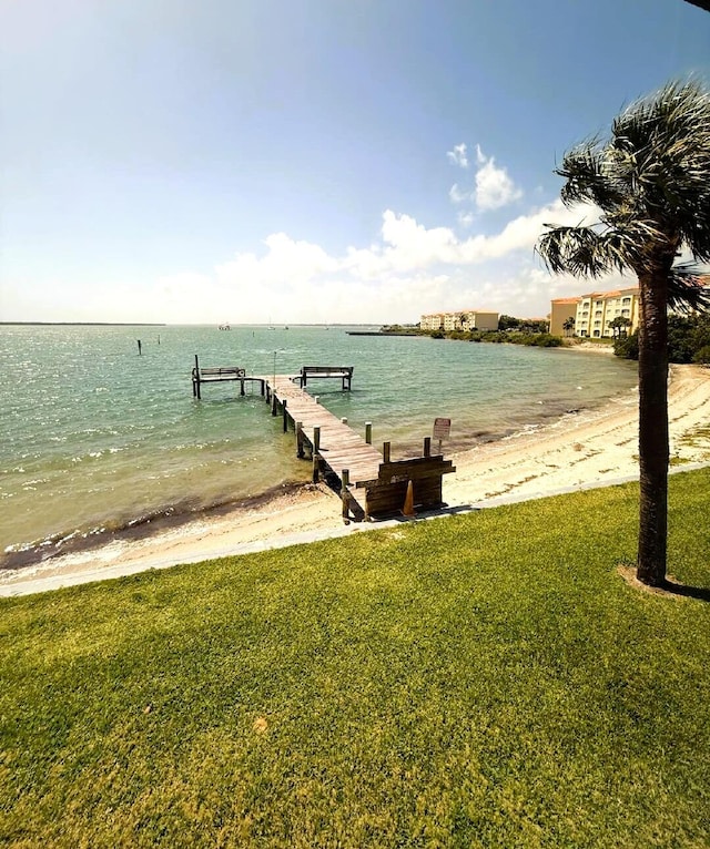 dock area featuring a lawn, a water view, and a view of the beach