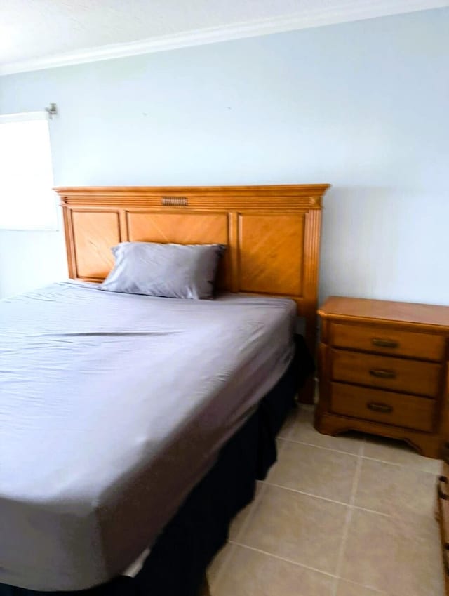 bedroom with ornamental molding and light tile patterned floors