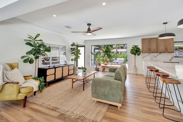 living area with a ceiling fan, visible vents, a healthy amount of sunlight, and light wood-style flooring