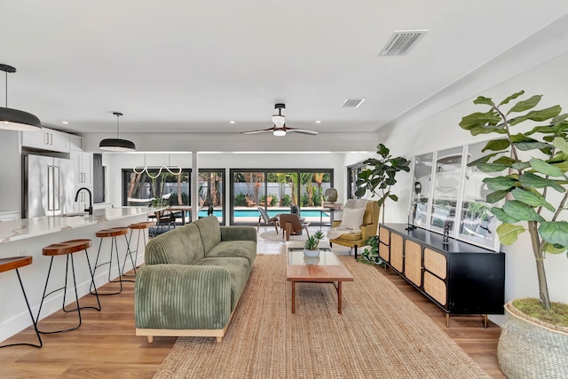 living area featuring ceiling fan, light wood finished floors, and visible vents