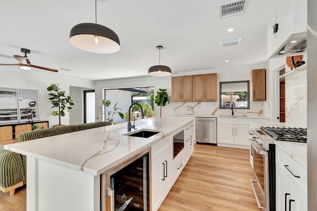 kitchen with a sink, appliances with stainless steel finishes, plenty of natural light, and beverage cooler