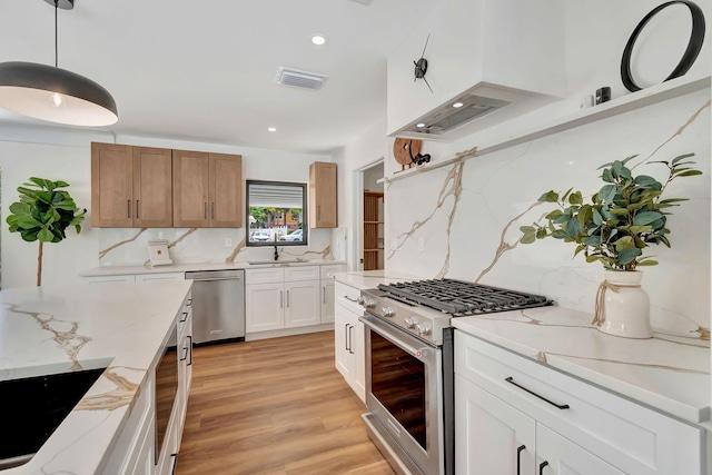 kitchen with light stone counters, stainless steel appliances, decorative backsplash, light wood-type flooring, and visible vents