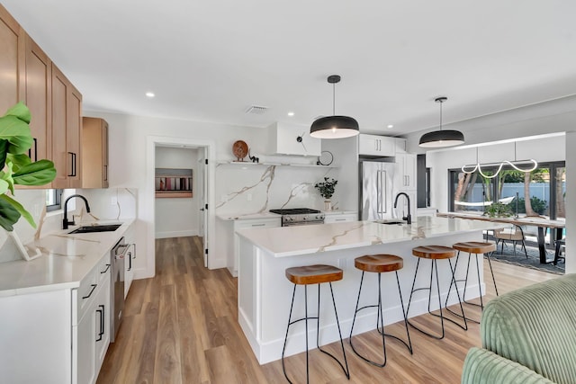 kitchen with a sink, a kitchen breakfast bar, stainless steel appliances, and light wood finished floors
