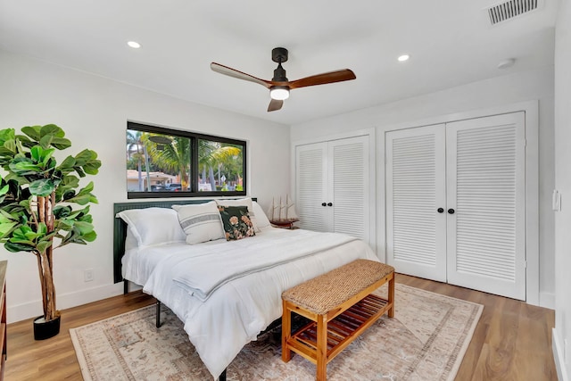 bedroom with ceiling fan, light wood finished floors, two closets, recessed lighting, and visible vents