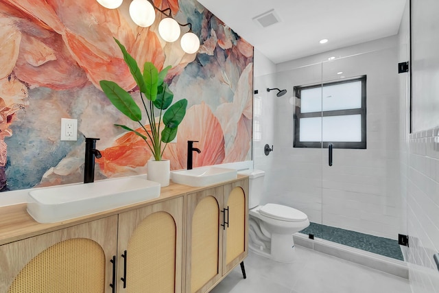 bathroom featuring double vanity, toilet, a shower stall, and a sink