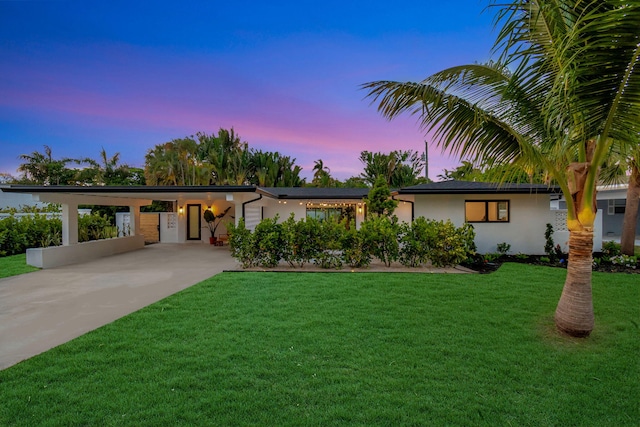 view of front of property featuring a carport, stucco siding, driveway, and a front lawn