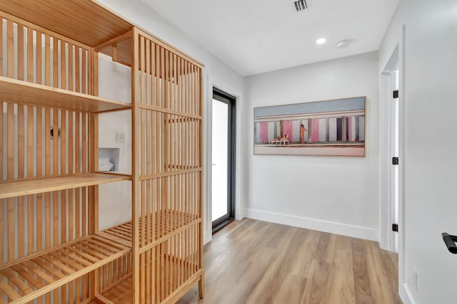 corridor with baseboards, visible vents, a wealth of natural light, and wood finished floors