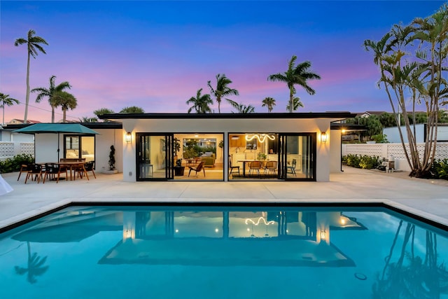 back of property featuring fence, a fenced in pool, a patio area, and stucco siding