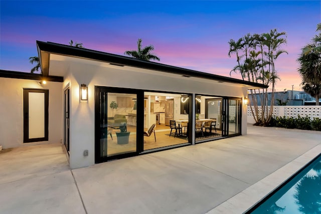 back of house featuring fence, a patio, stucco siding, and an outdoor pool