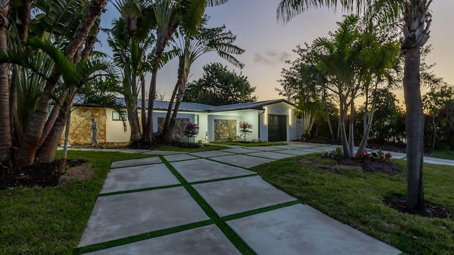 200 SW 12th St, Boca Raton, FL 33432 - view of front of house with an attached garage, a front lawn, stucco siding, concrete driveway, and metal roof