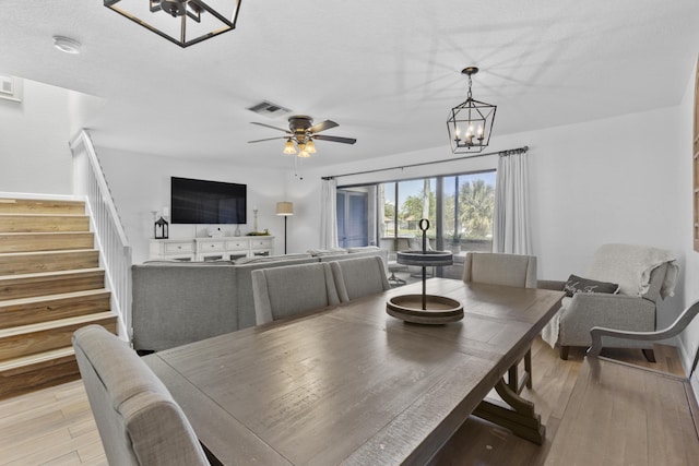 1693 Woodbridge Lakes Cir, West Palm Beach, FL 33406 - dining room with stairs, light wood-style flooring, a ceiling fan, and a chandelier
