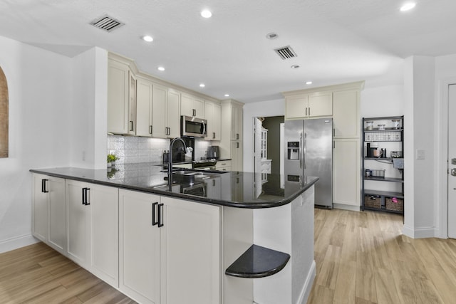 1693 Woodbridge Lakes Cir, West Palm Beach, FL 33406 - kitchen with appliances with stainless steel finishes, a sink, light wood-type flooring, a peninsula, and backsplash