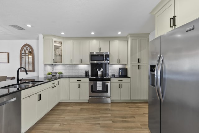 1693 Woodbridge Lakes Cir, West Palm Beach, FL 33406 - kitchen featuring appliances with stainless steel finishes, a sink, light wood-type flooring, decorative backsplash, and glass insert cabinets
