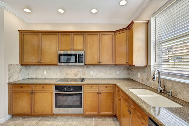 kitchen featuring brown cabinetry, light stone countertops, a sink, stainless steel appliances, and recessed lighting