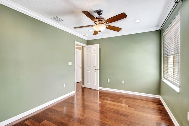 empty room featuring visible vents, a ceiling fan, wood finished floors, and a healthy amount of sunlight