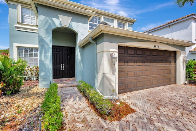 view of front of home with a garage, decorative driveway, and stucco siding