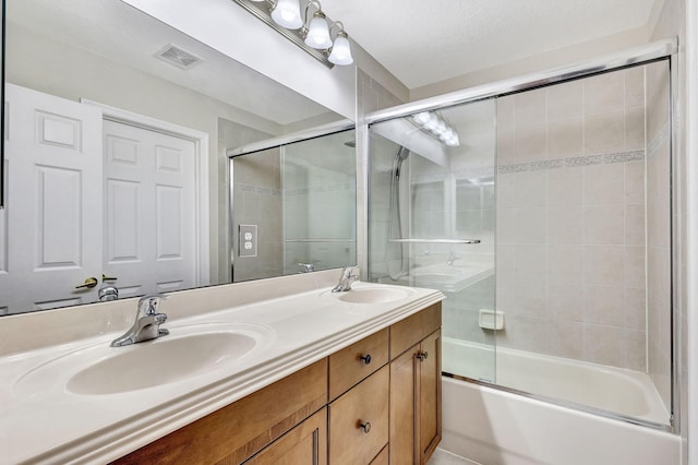 full bathroom with double vanity, shower / bath combination with glass door, visible vents, and a sink