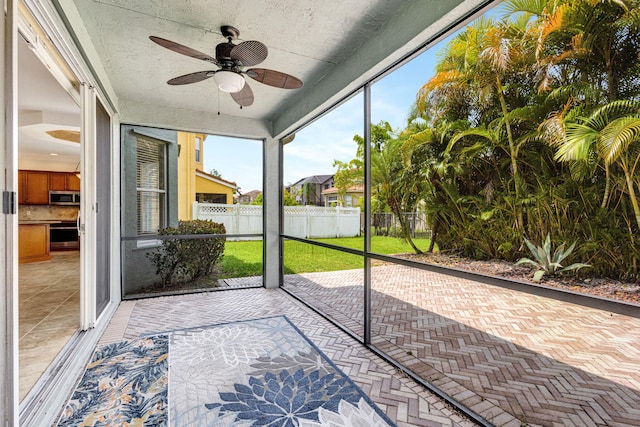 unfurnished sunroom with ceiling fan