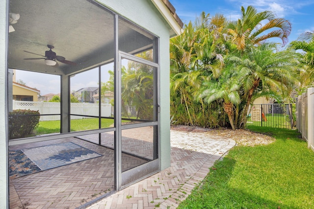 exterior space featuring a sunroom, a ceiling fan, and a fenced backyard