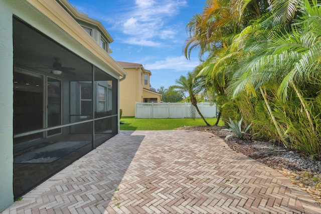 view of patio / terrace with fence, a ceiling fan, and a sunroom
