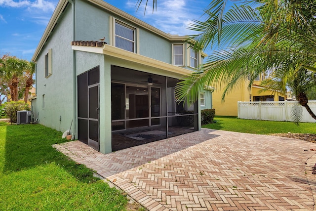 rear view of house featuring a sunroom, stucco siding, a yard, and a patio