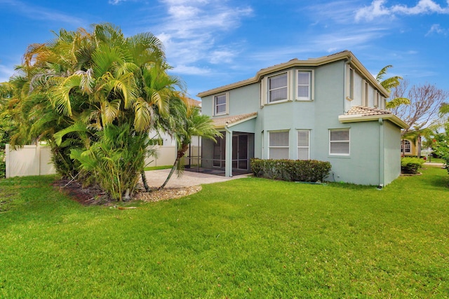 back of property featuring fence, a tile roof, stucco siding, a sunroom, and a yard