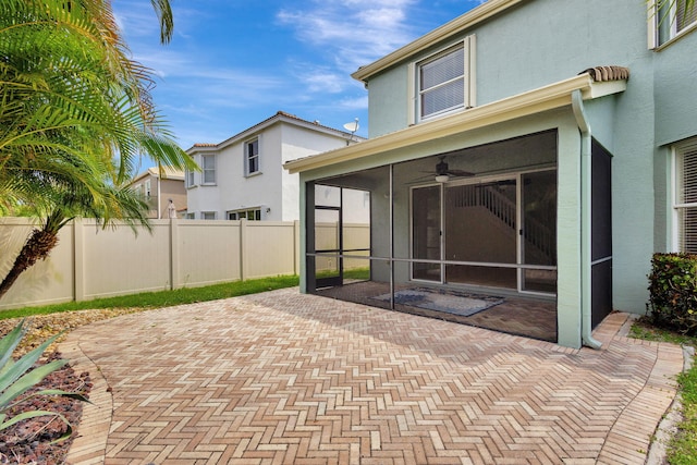 exterior space featuring a sunroom, ceiling fan, and fence