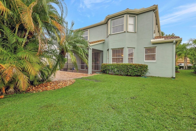 rear view of property with a lawn, stucco siding, and a tile roof