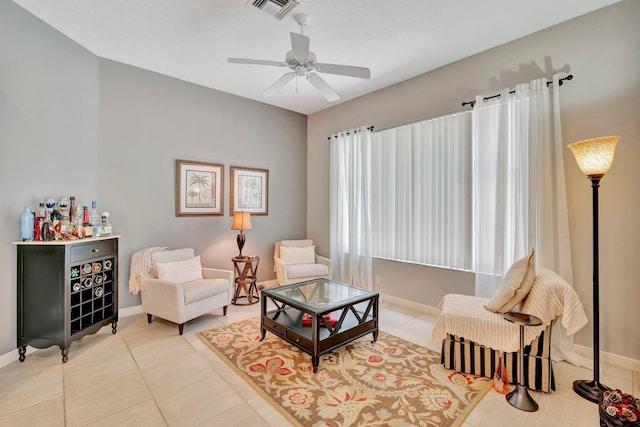 living area featuring tile patterned floors, visible vents, baseboards, and a ceiling fan