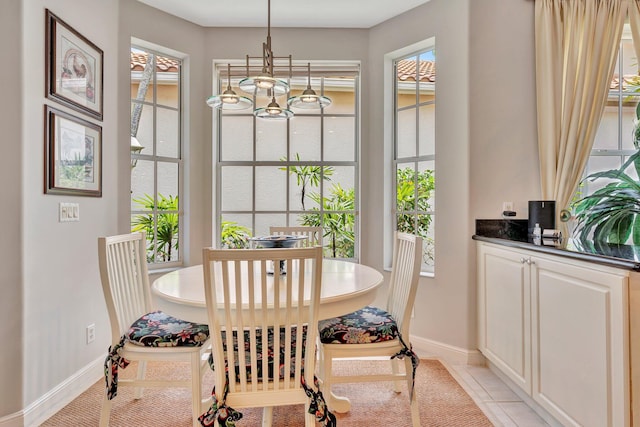 dining area with an inviting chandelier, light tile patterned flooring, and baseboards