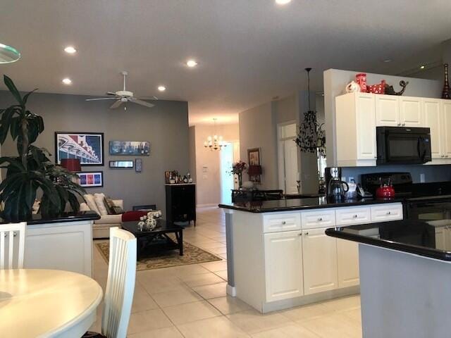 kitchen with dark countertops, white cabinetry, ceiling fan with notable chandelier, and black appliances