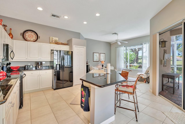 kitchen with black appliances, dark countertops, a healthy amount of sunlight, and visible vents