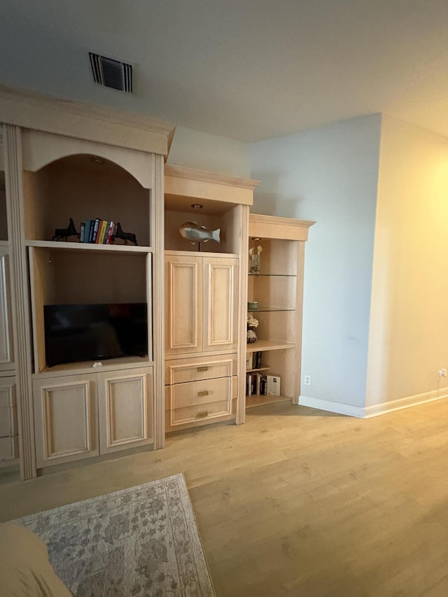 living area with baseboards, light wood-style flooring, and visible vents