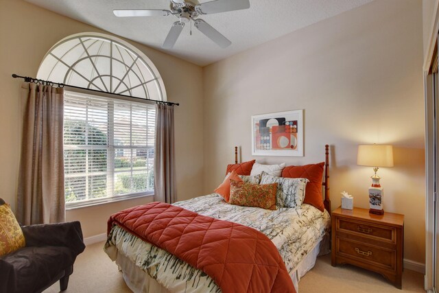 bedroom with light carpet, baseboards, and a ceiling fan