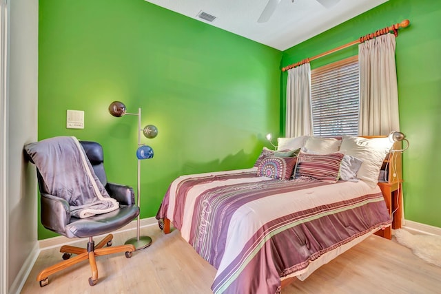 bedroom with baseboards, ceiling fan, visible vents, and wood finished floors