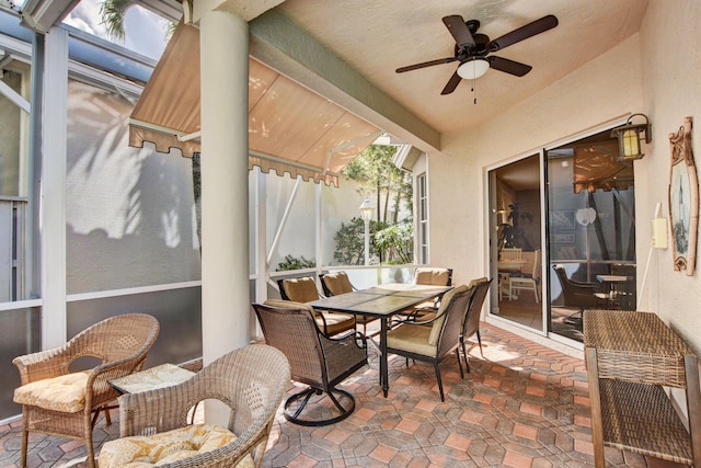 sunroom / solarium with outdoor dining area and a ceiling fan