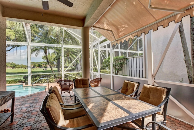 sunroom with ceiling fan, golf course view, and a swimming pool