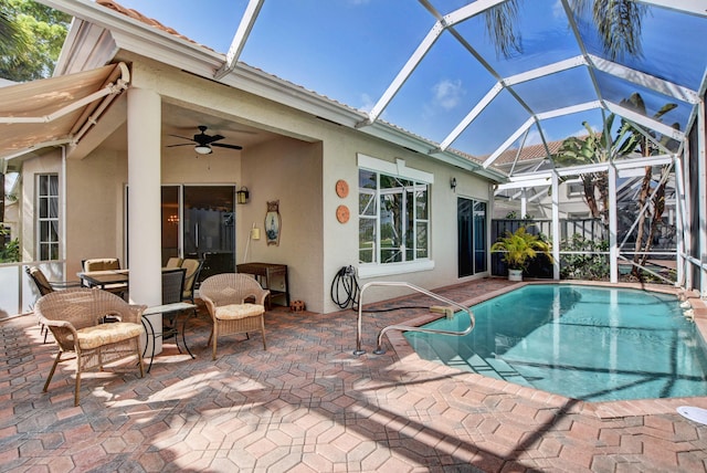 pool featuring glass enclosure, a patio, and ceiling fan