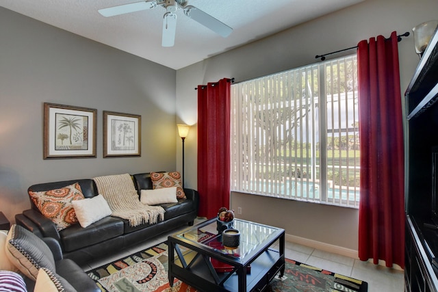 tiled living area with ceiling fan and baseboards