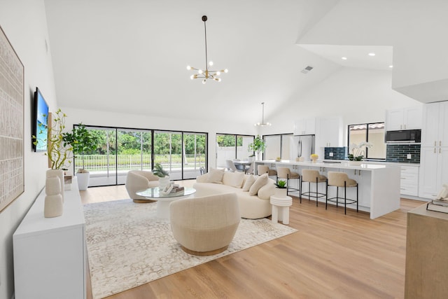 2795 Hawthorne Ln, West Palm Beach, FL 33409 - living room featuring high vaulted ceiling, a chandelier, light wood-style flooring, recessed lighting, and plenty of natural light