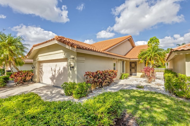 2795 Hawthorne Ln, West Palm Beach, FL 33409 - view of front of property with an attached garage, stucco siding, a tiled roof, and driveway