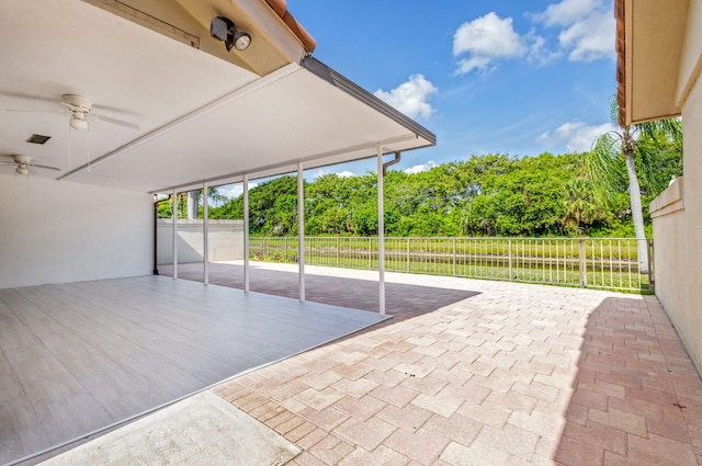 2795 Hawthorne Ln, West Palm Beach, FL 33409 - fenced backyard with ceiling fan, a patio area, a carport, view of scattered trees, and driveway