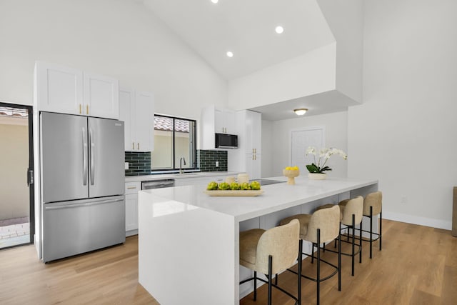 2795 Hawthorne Ln, West Palm Beach, FL 33409 - kitchen with appliances with stainless steel finishes, high vaulted ceiling, white cabinets, a sink, and a breakfast bar area