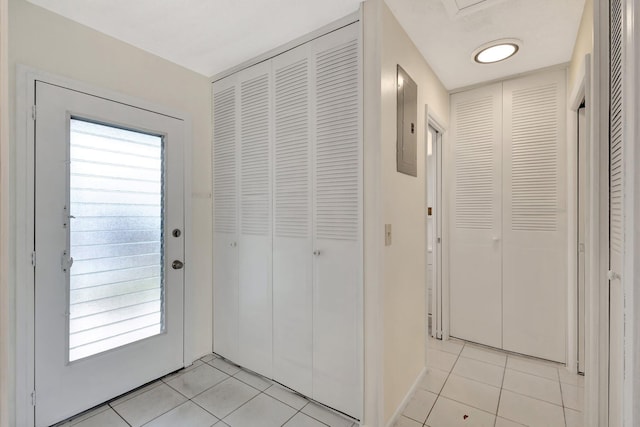 entryway with baseboards, light tile patterned floors, and electric panel