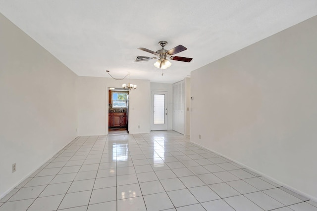 empty room featuring light tile patterned flooring, baseboards, and ceiling fan with notable chandelier